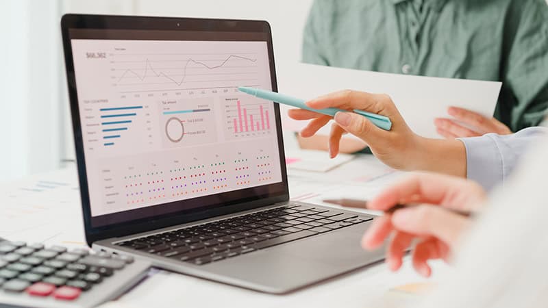 Personer som analyserer data på en laptop med grafer og diagrammer.