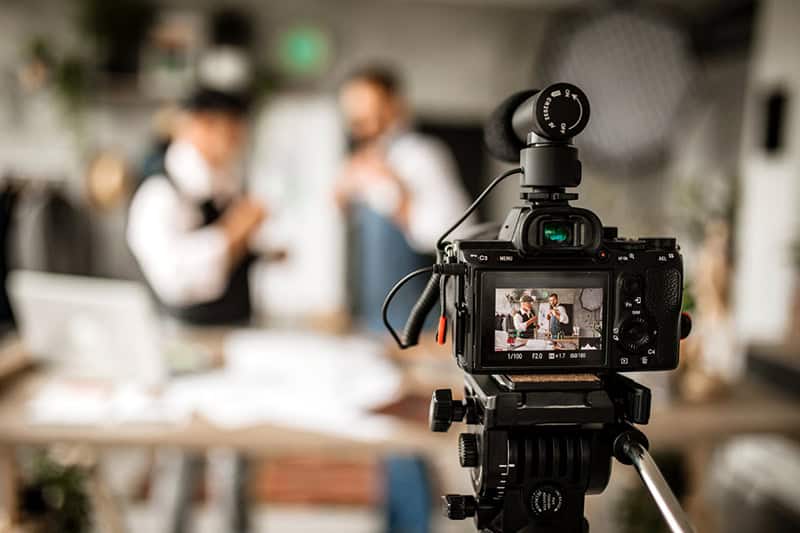 Kamera som filmer en presentasjon under forberedelser til et webinar, med fokus på bruk av riktig utstyr for å sikre høy kvalitet på nettarrangementet.