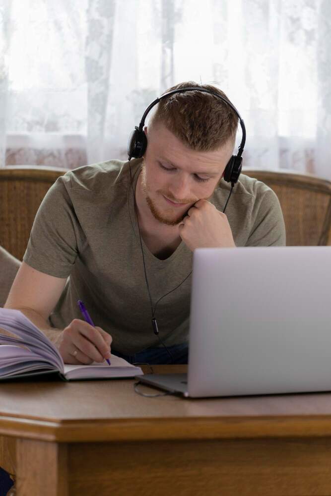 Mann sitter foran datamaskin og noterer ned hva han lærer på et nettkurs
